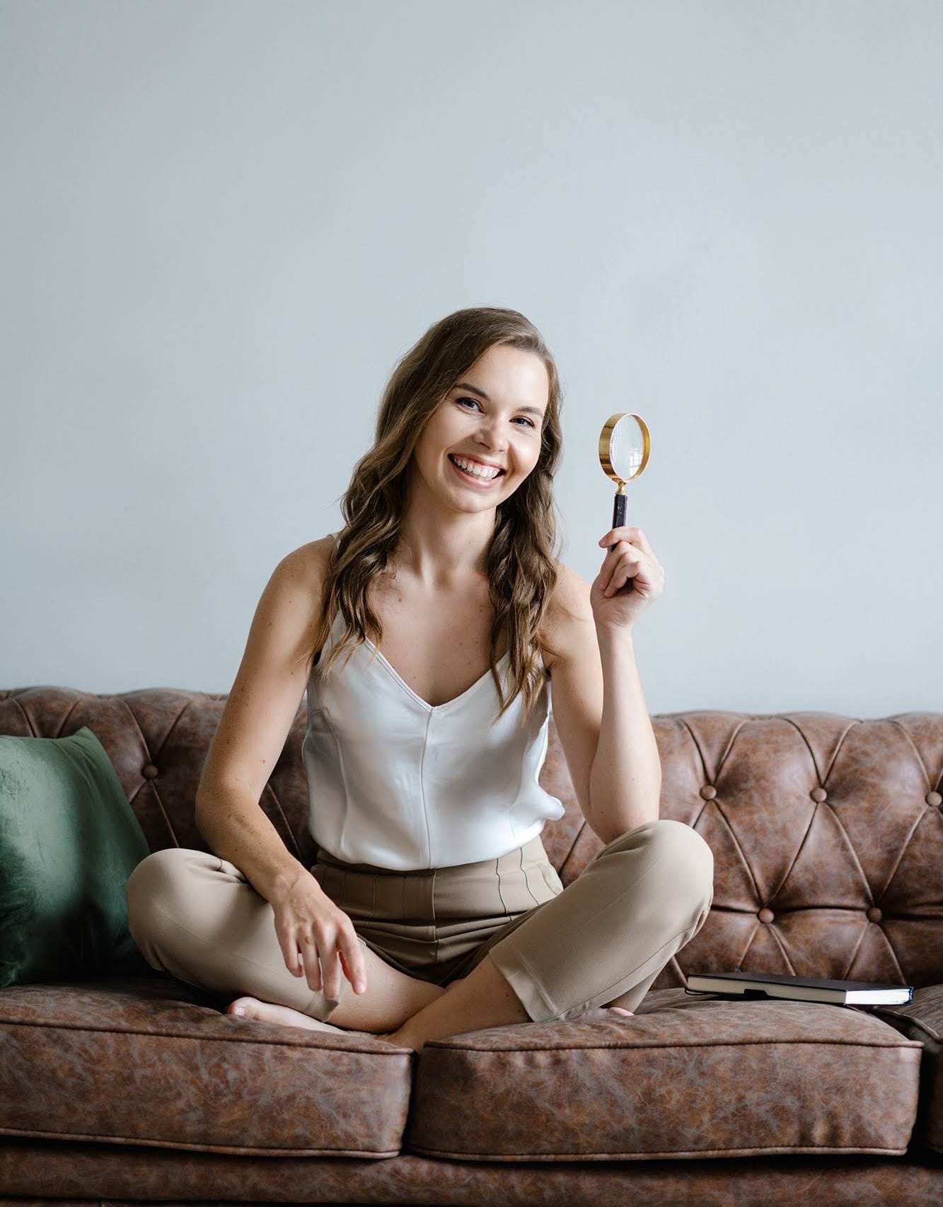 grafikos dizainerė Simonos Morozova su padidinimo stiklu ant sofos